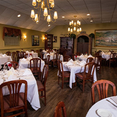 a row of pristinely placed table settings and roses lining the center of the table